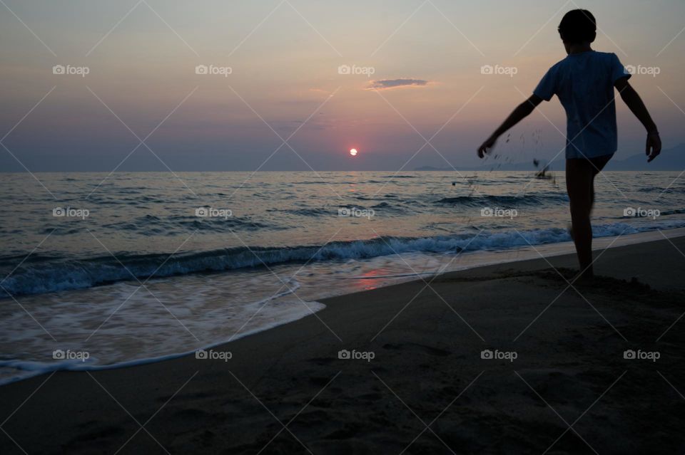 silhouette of child playing at sunset on the beach