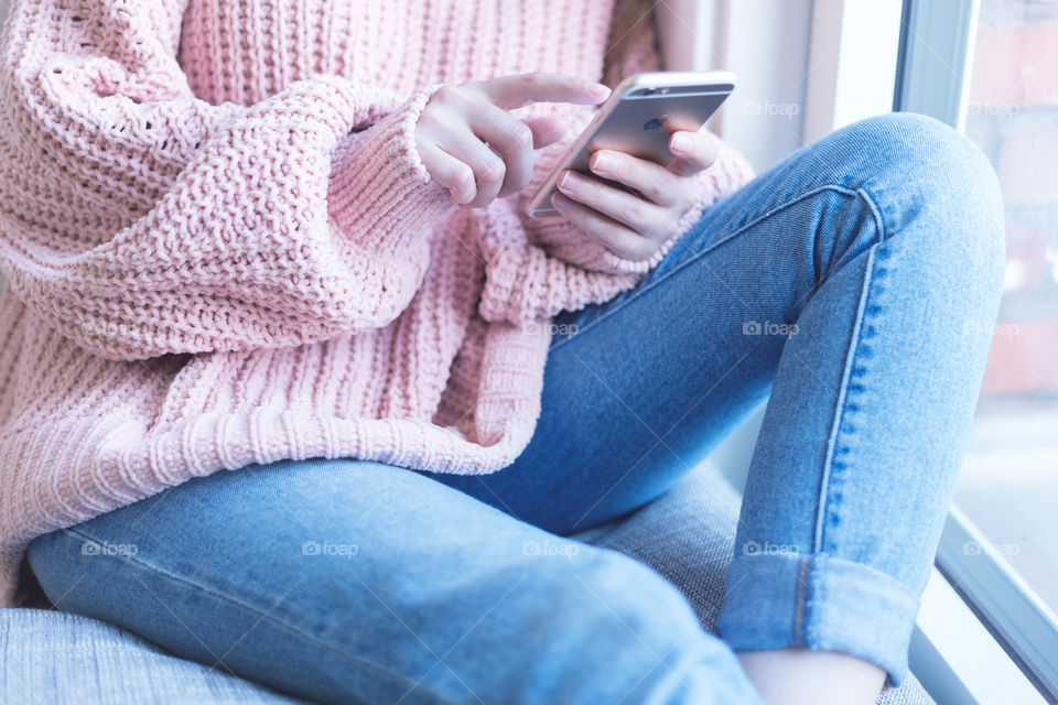 A woman wearing a cozy sweater and using mobile 