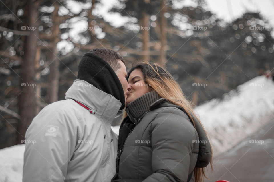 Couple kissing in the snow forest 