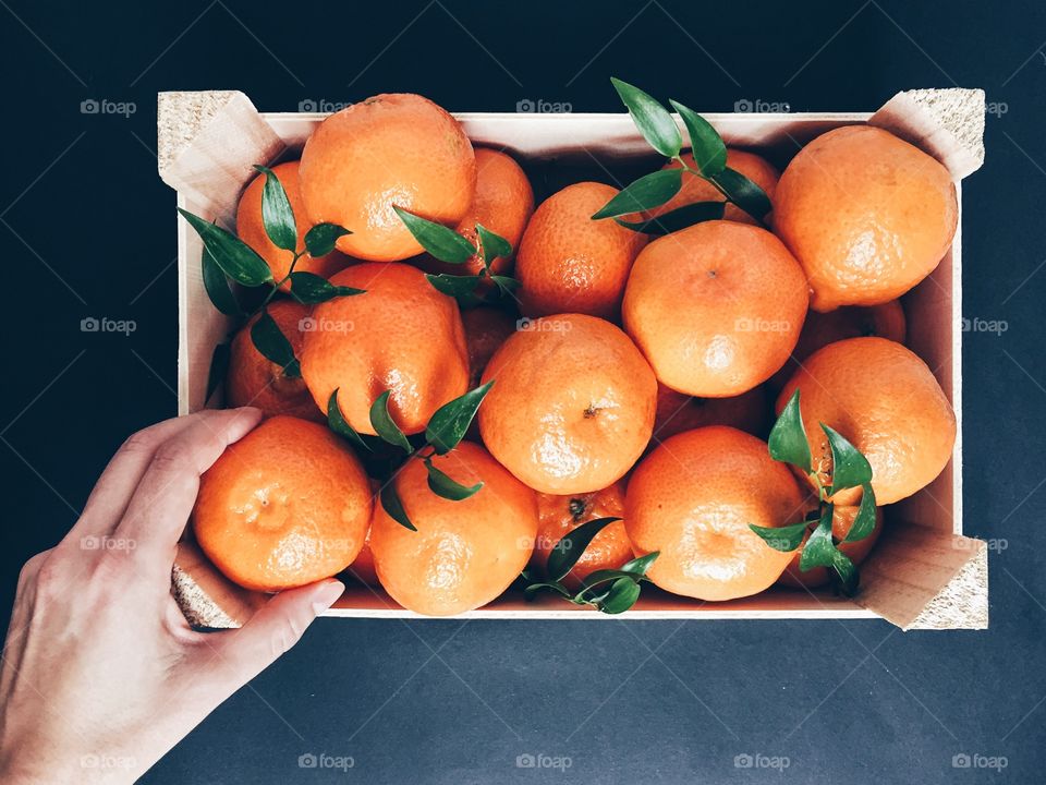 Woman hand taking orange from fruit basket