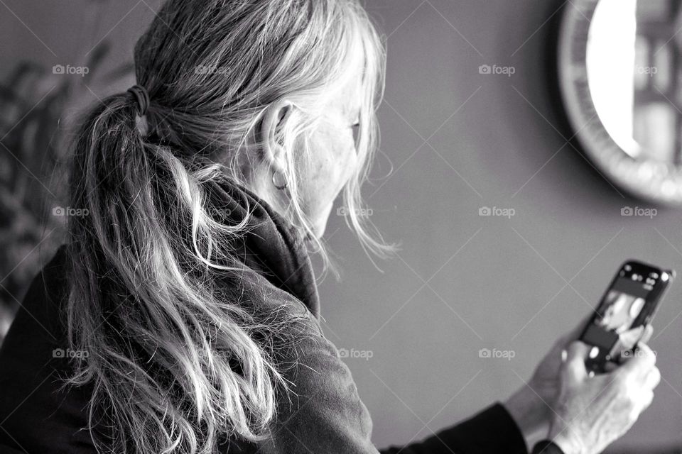 Black and white photo of woman with long hair using mobile phone 