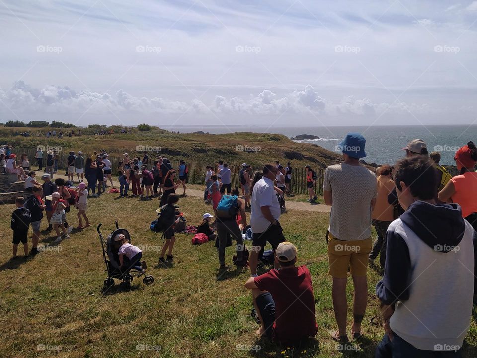 A crowd of spectators await runners at the finish of a seaside race.