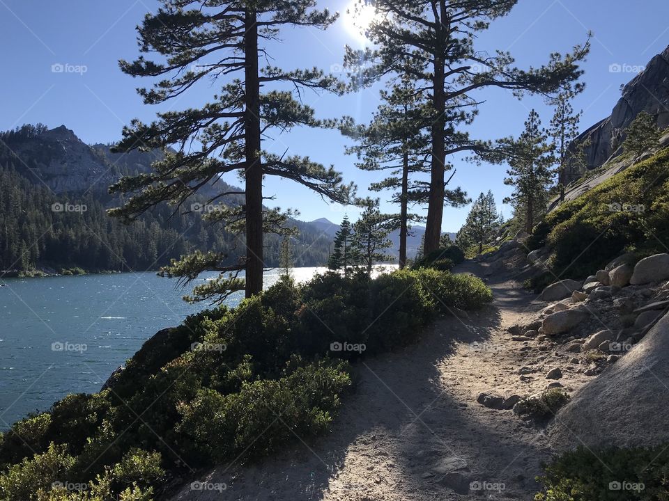 Looking back at the completed trail as the sun begins to lower itself down. Hiking along the mountains, the pine trees and the picturesque lake. 