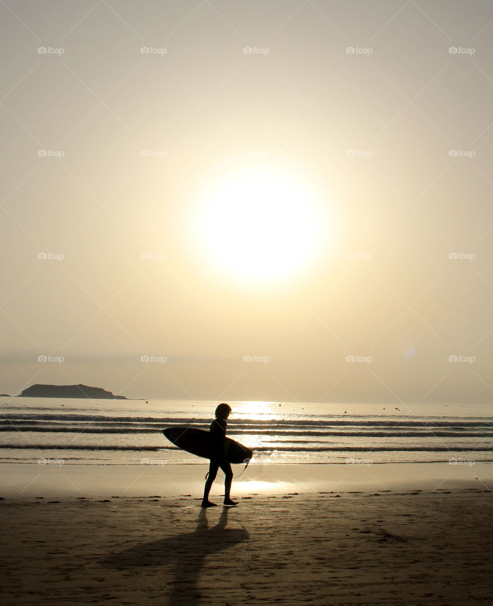 Surfer on the beach at sunset 