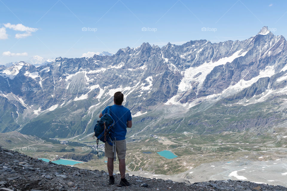 Hiking in Cervinia Italy, man watching the stunning view of the mountains and lakes 