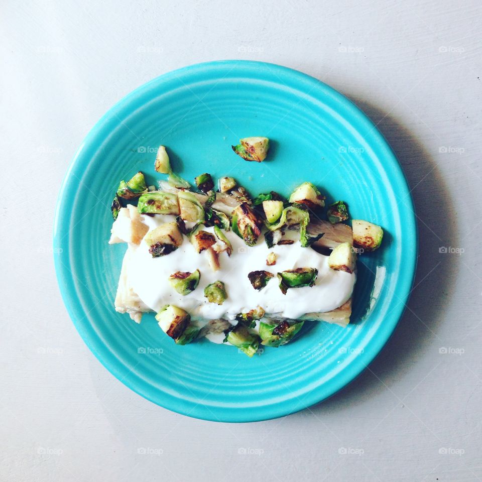 A homemade seared Mahi Mahi filet rests beneath a bed of sour cream and sautéed Brussels sprouts. 