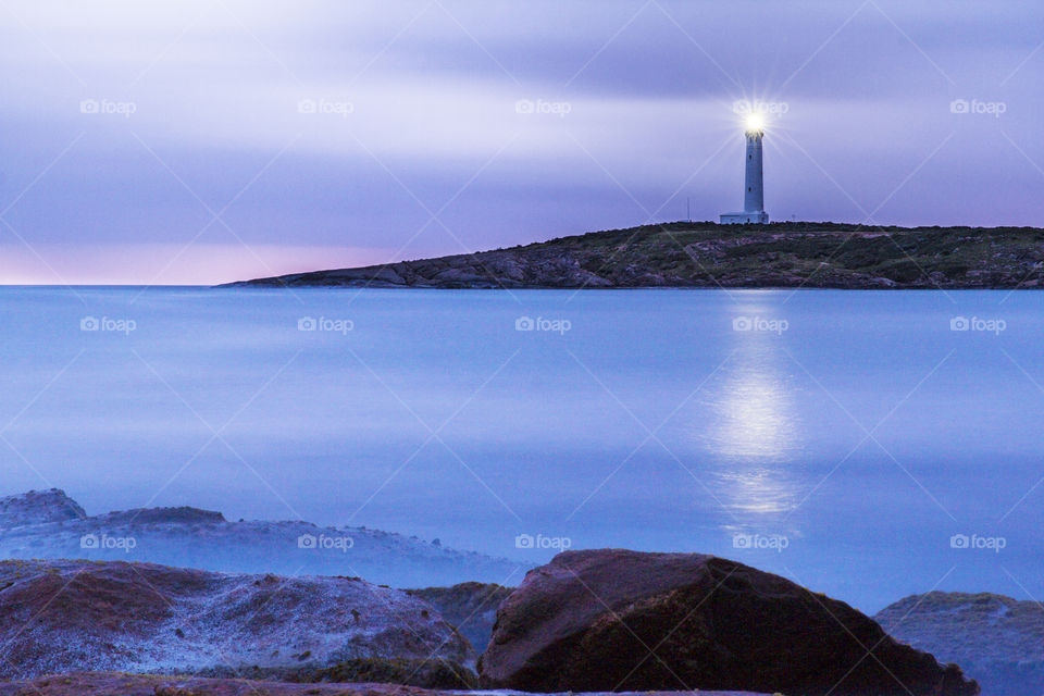Cape Leeuwin lighthouse dwarfed by rocky outcrops in the bay at Augusta in South West Western Australia