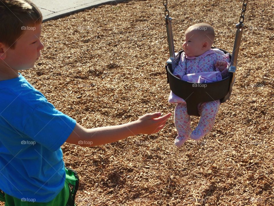 Big Brother Pushing Baby In A Swing