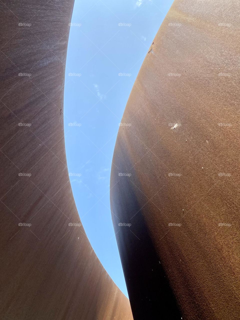 Looking up at the sky from beneath a large metal sculpture 