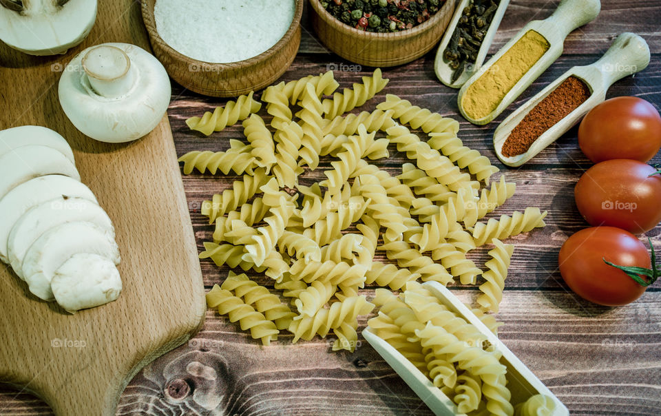 Raw pasta with ingredients and wooden accessories