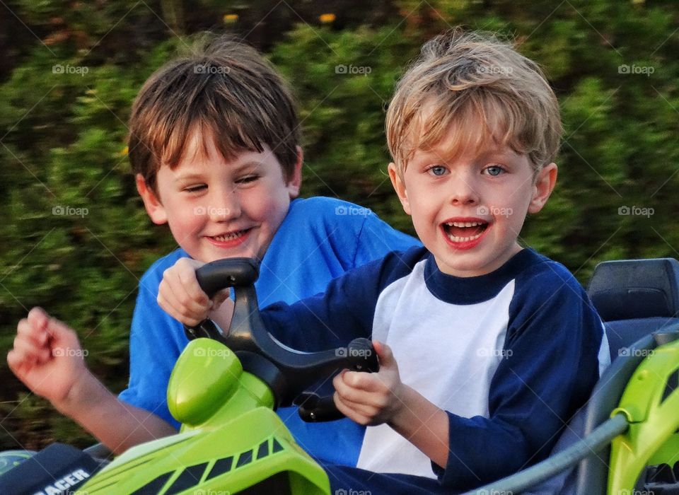 Two boys driving toy vehicle