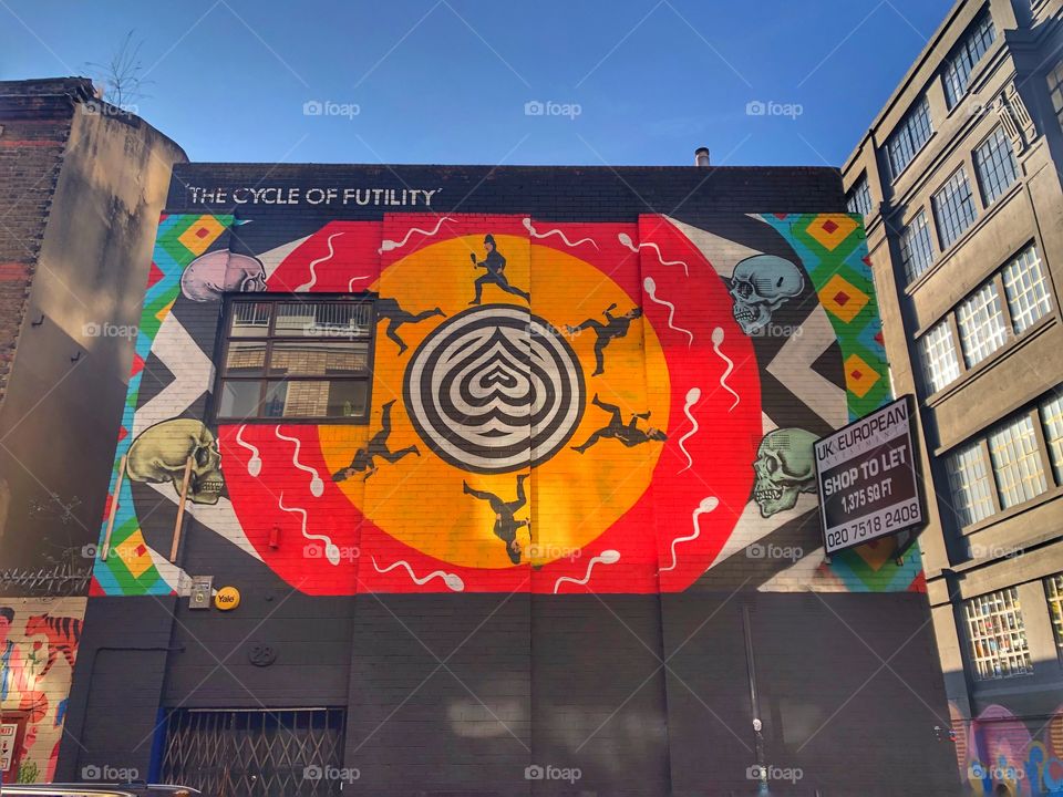 The cycle of futility augmented reality mural by street artist INSA on black building exterior with blue sky and copy space