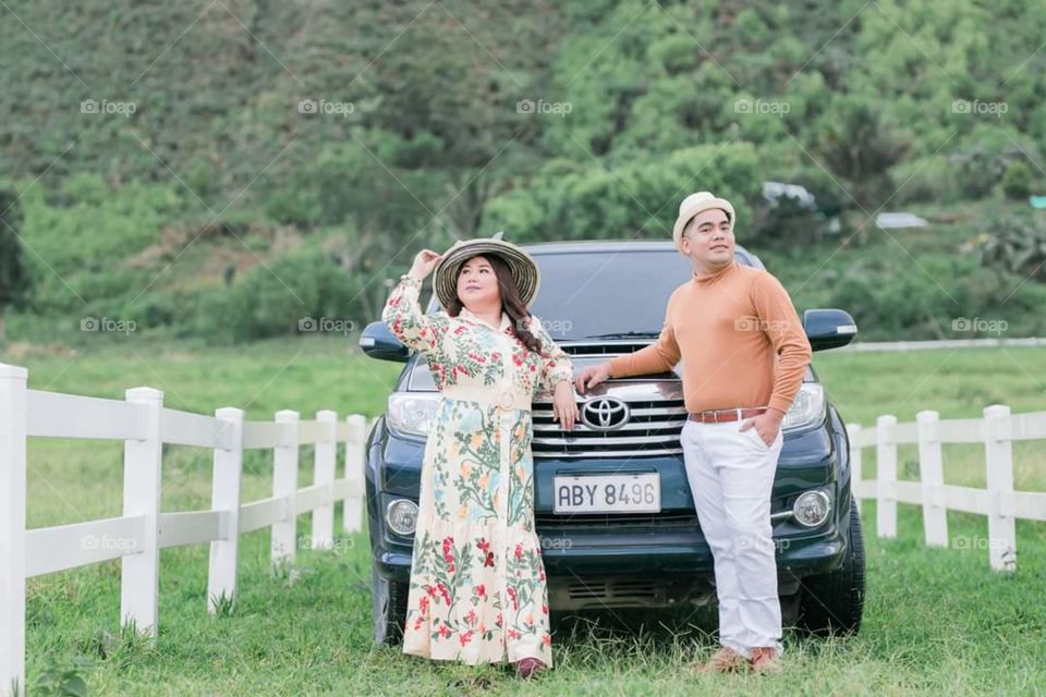 two lovers standing in front of their Toyota car