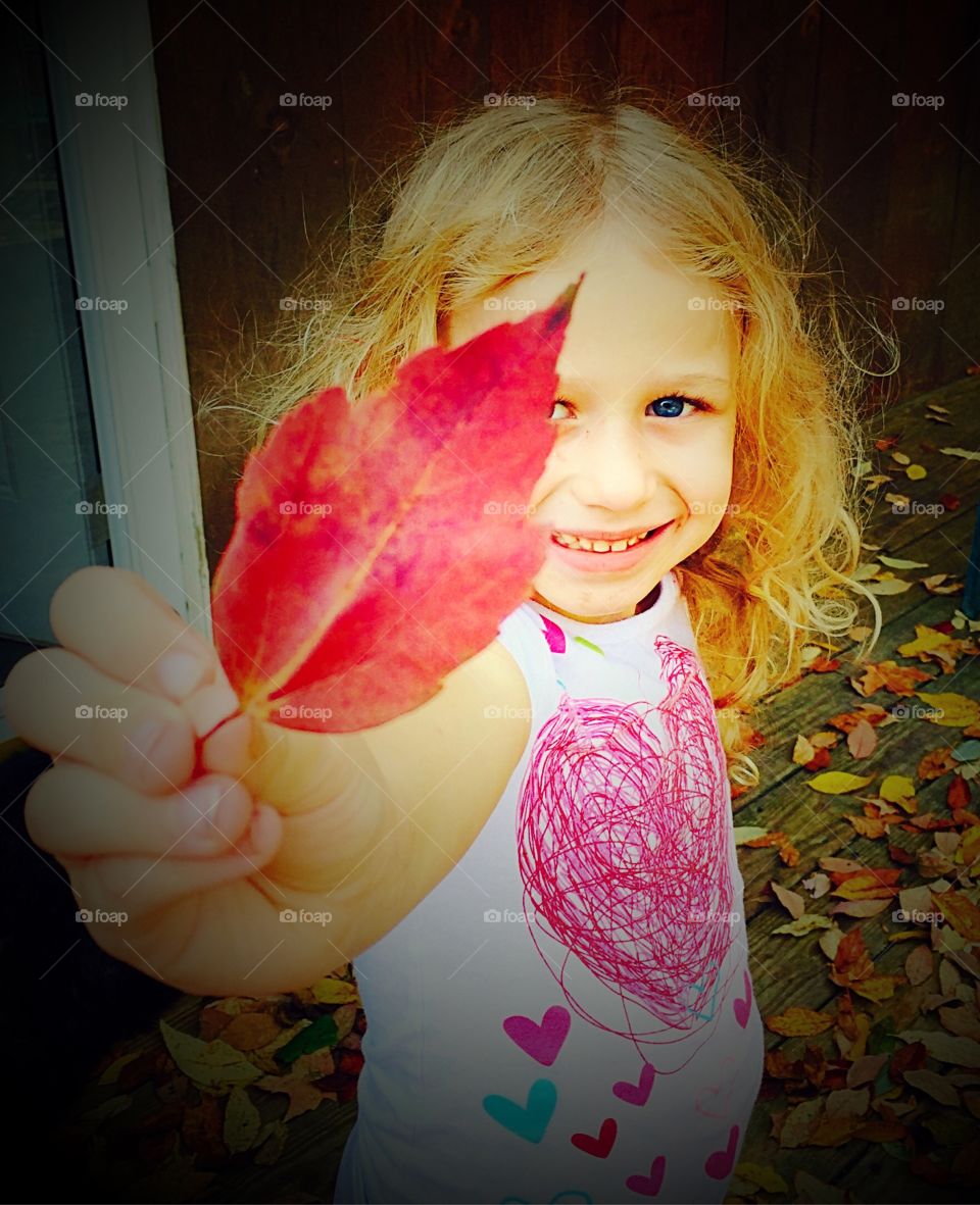 Smiling girl holding autumn leaf