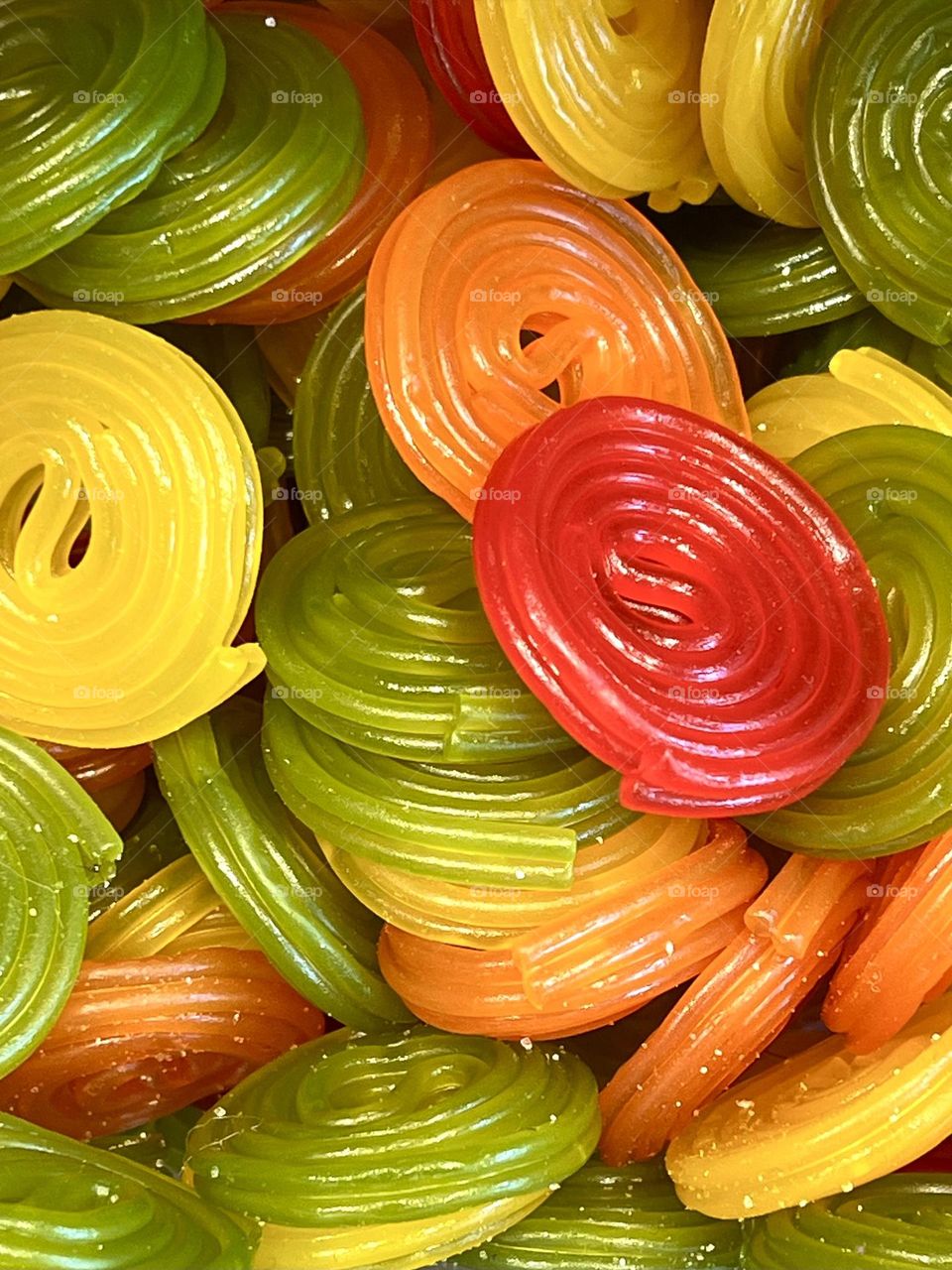 Bright fruit jelly rolls in red, yellow, green and orange colors, close-up. Juicy colors and glossy texture make them appetizing.