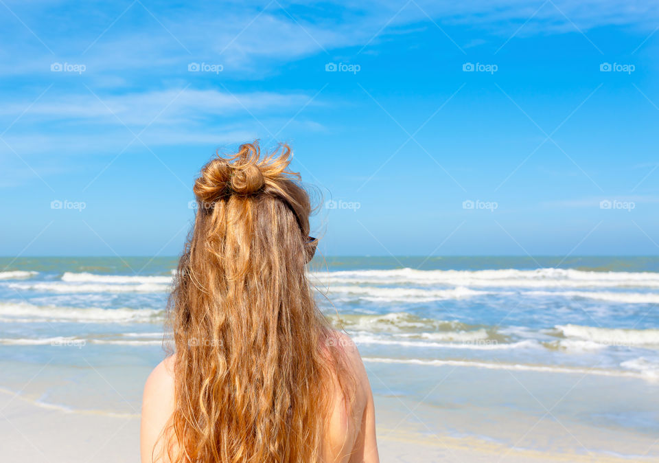 Young female person enjoys sunny day on vacation at seaside