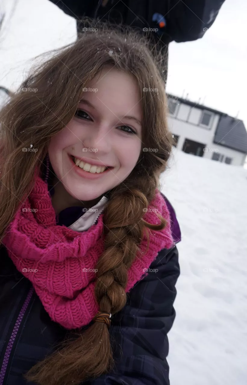 Girl in winter fashion in the snow looking into the camera