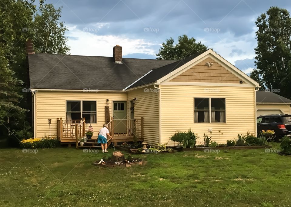 Storm clouds gather over this house in Bakersfield, Vermont.  Woman outside trying to get her yard work done before the rain comes. 