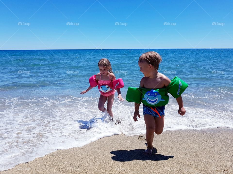 Two kids running in see shore