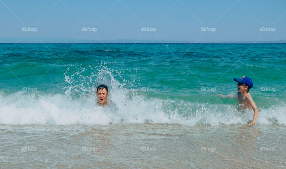 People have fun in sea water waves and splash in the summer day.