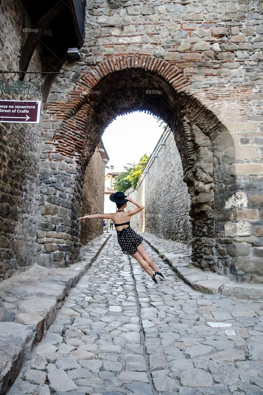 A girl with hat jumps on the street