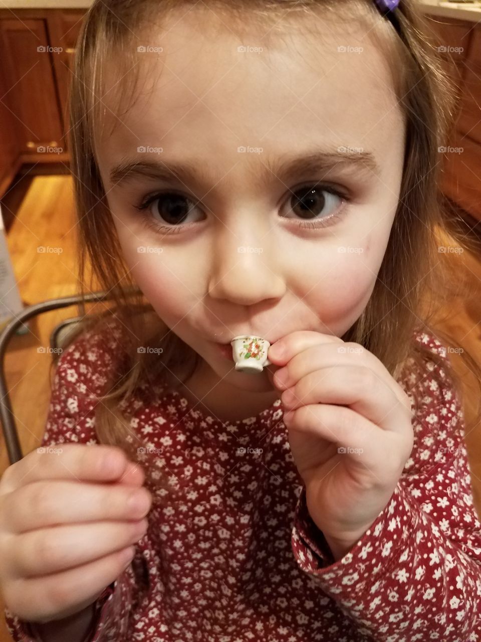 Little girl drinking tea from small cup