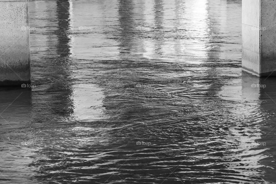 Water flowing under bridge black and white