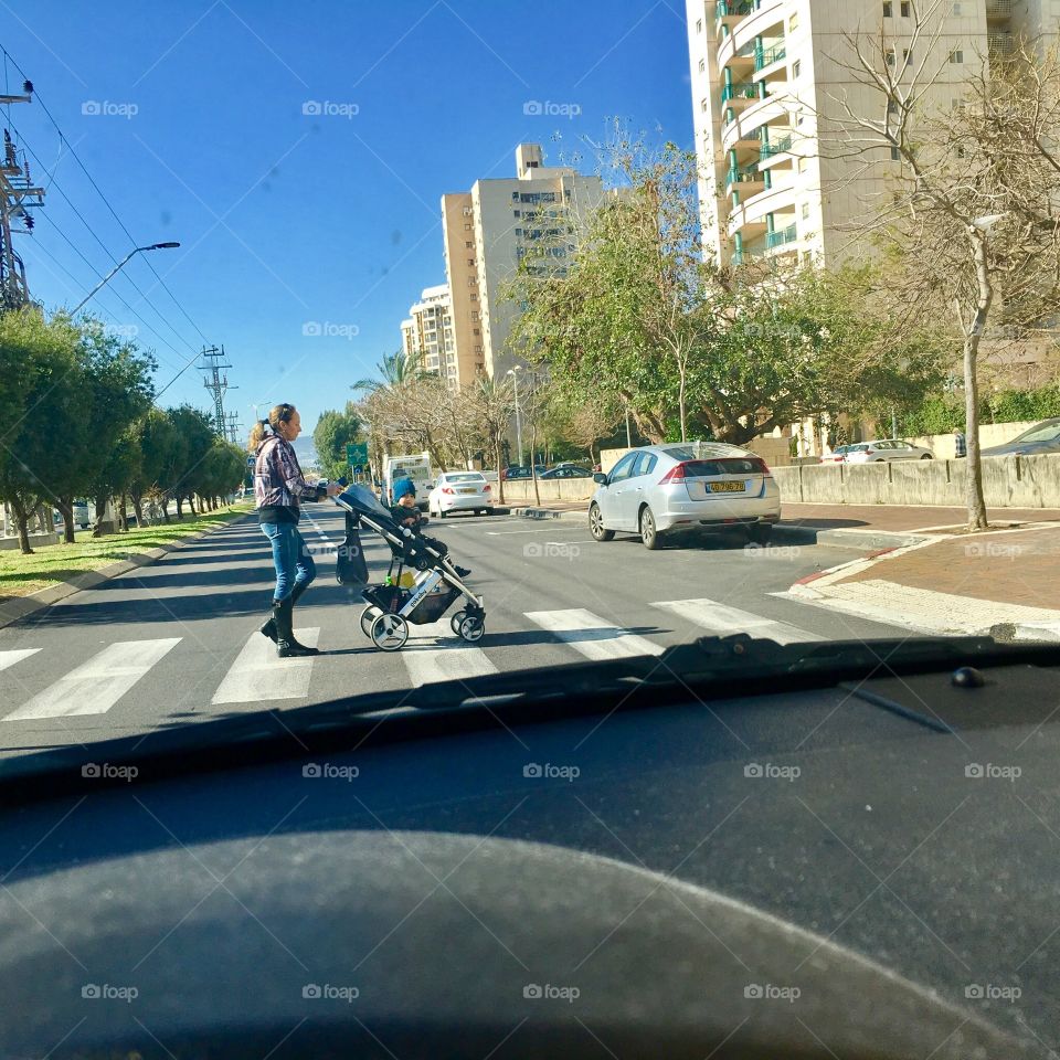A vehicle stops at half a crossing to mother and baby