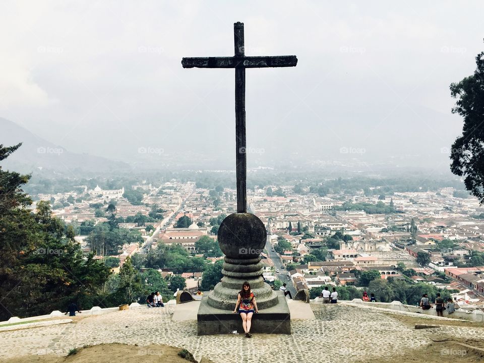 Young woman standing in front of the cerro de la cruz overlooking the beautiful city of Antigua, Guatemela on a cloudy day