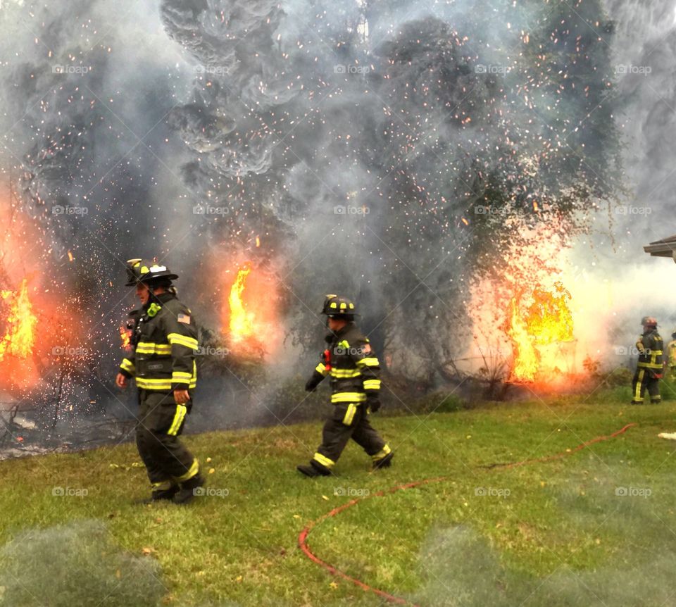 Brave firefighters. Brave firefighters combating a brush fire started by lightning dangerously close to a home.