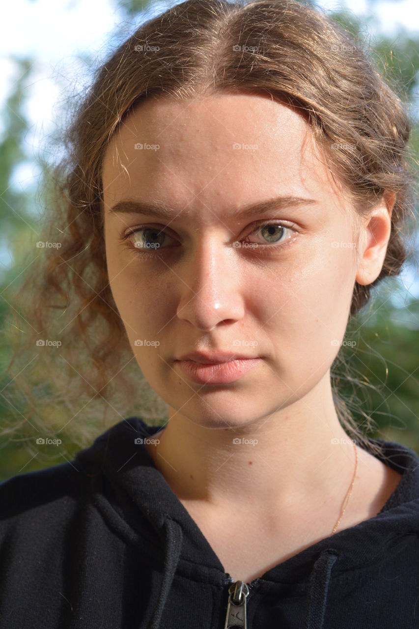 brunette girl beautiful portrait close up in sunlight outdoor green background