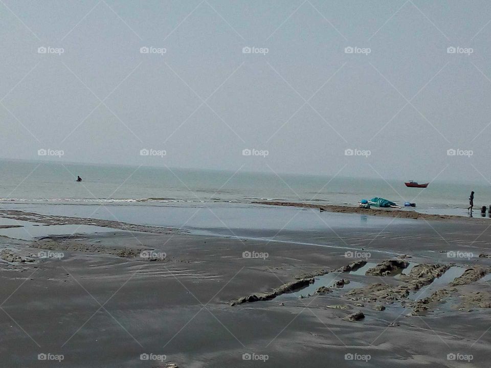 This is a sea beach with fishing net and boats far away in West Bengal