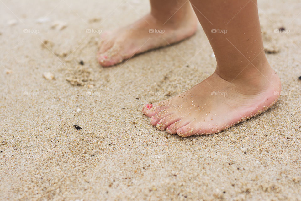 child feet in sand. little girl barefoot in sand