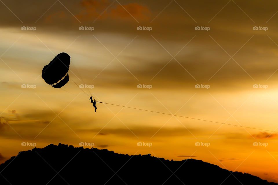 Sunset flying time with upward parachute silhouette