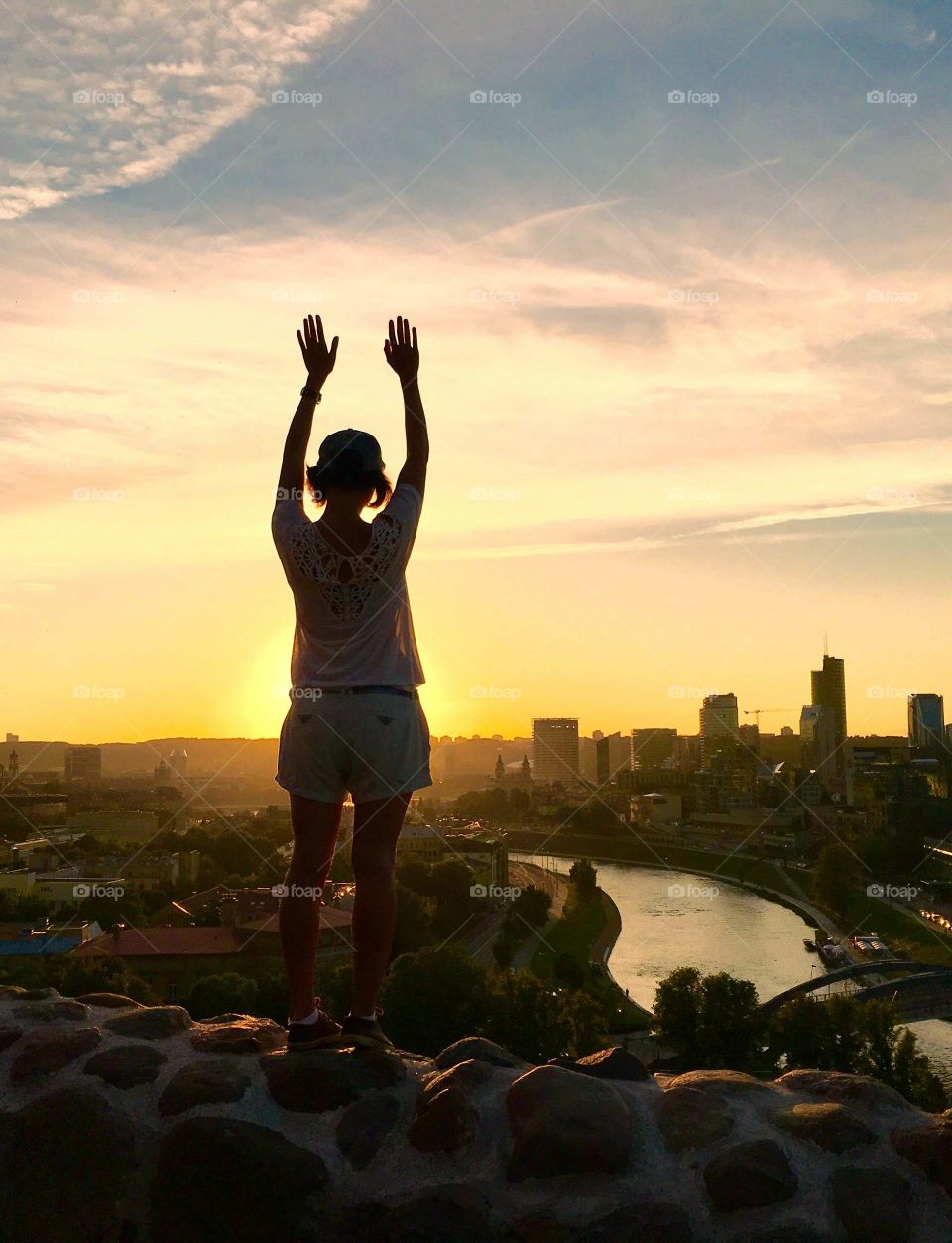 Silhouette of happy girl, enjoying the sunset on the top over the Vilnius. 