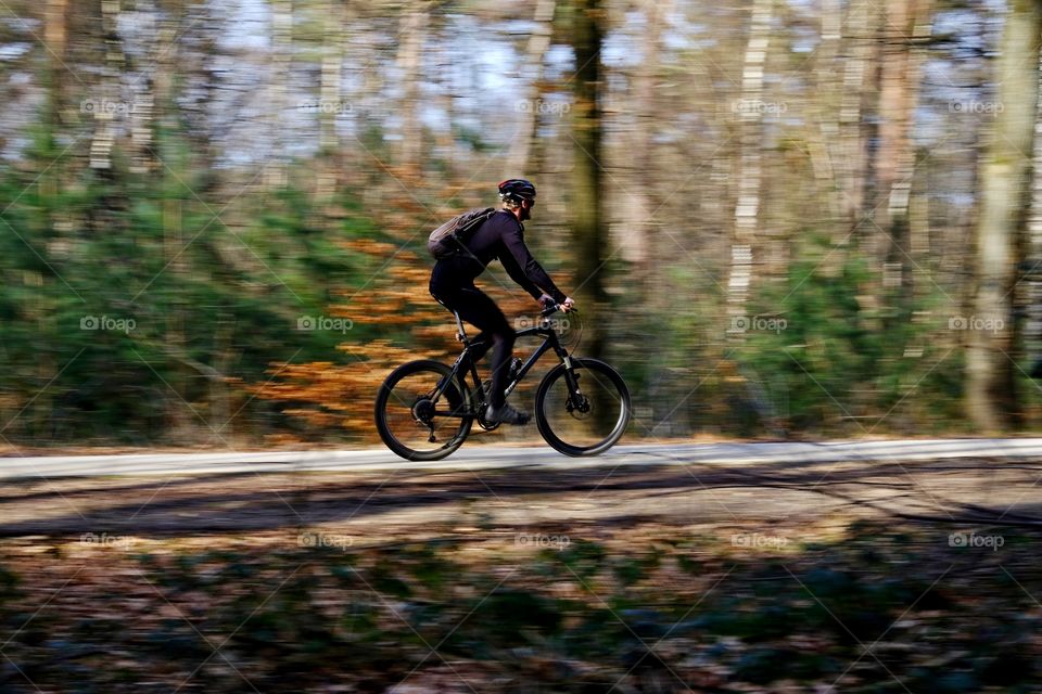 Man riding his mountain bike through a forest. 