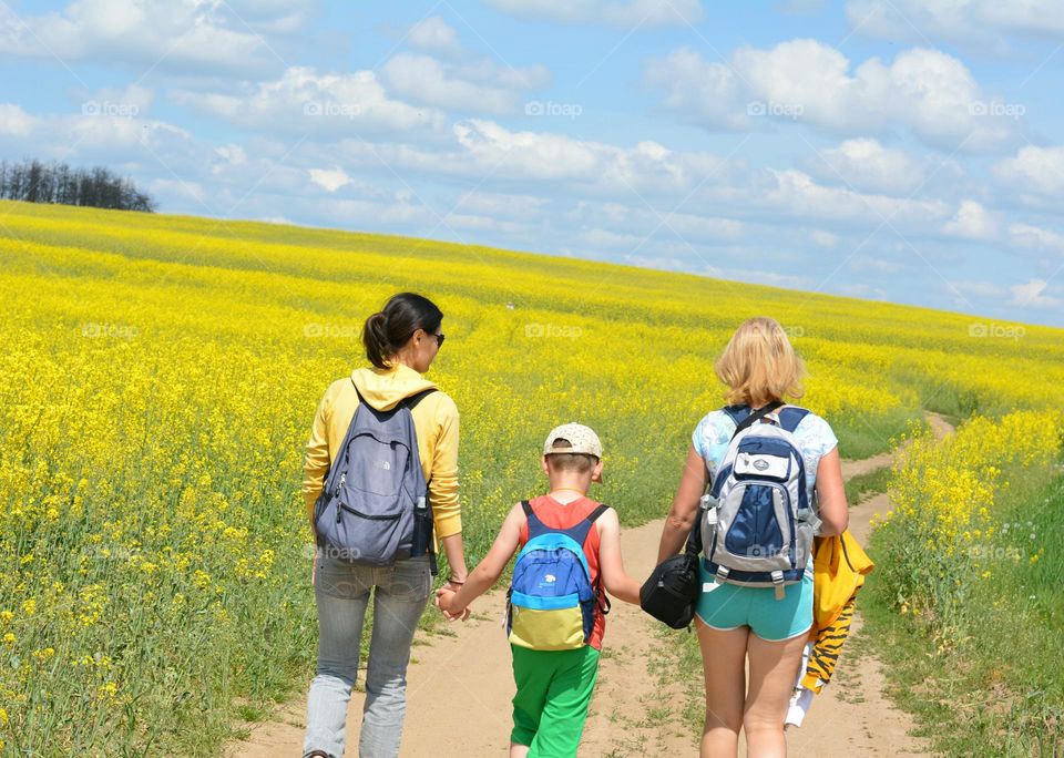 family walking outside rapeseed field summer time