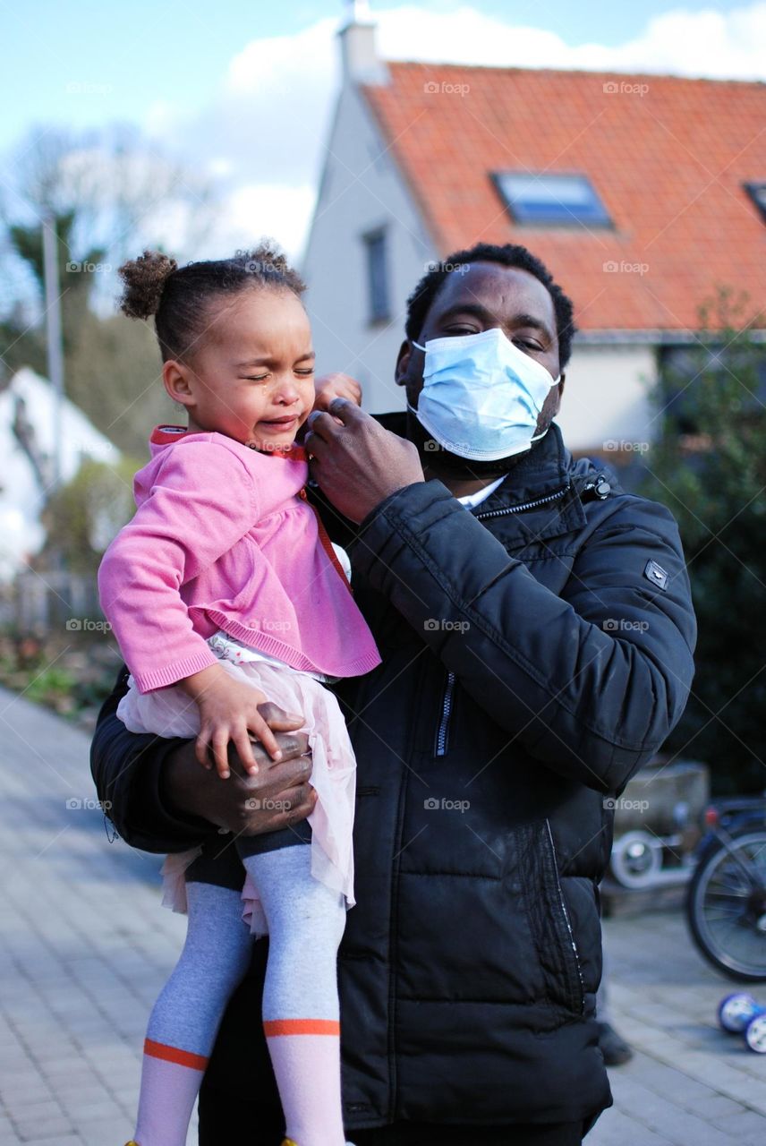 Black father holding his daughter who is crying 