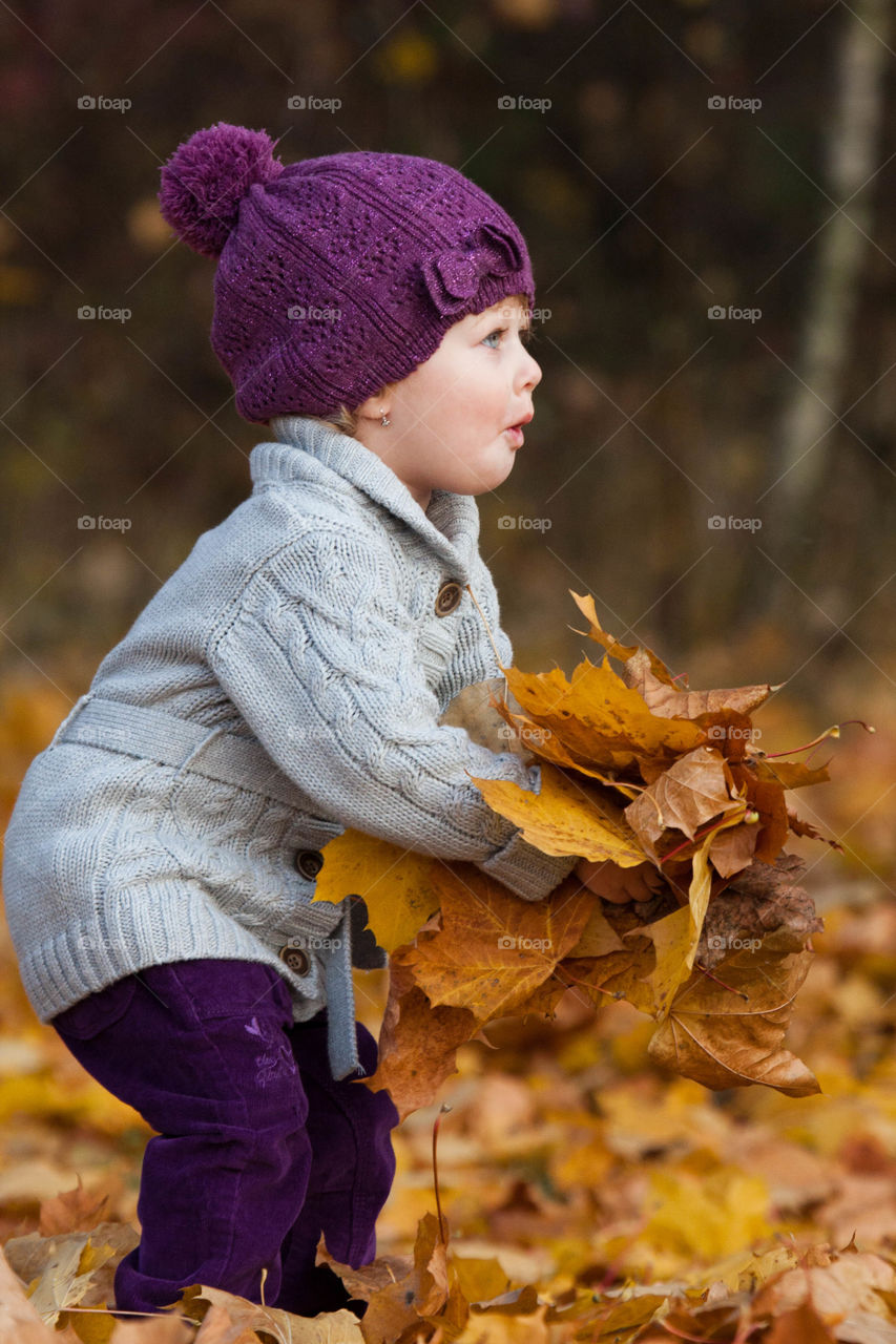 Cute baby holding autumn leaf in hand