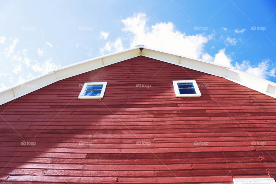 A huge barn with a window reflecting a perfect summer sky