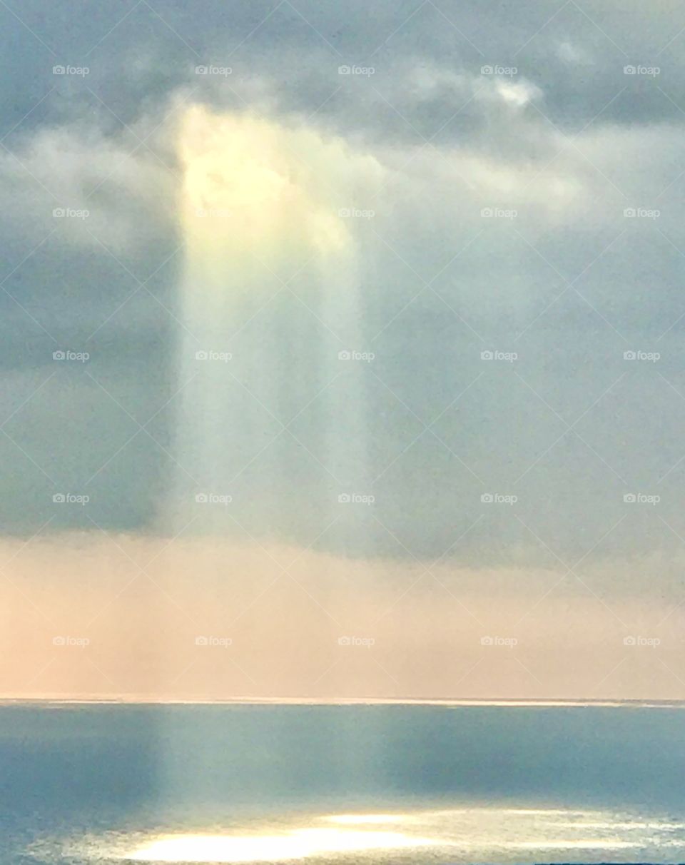 Sun rays spilling through clouds on ocean