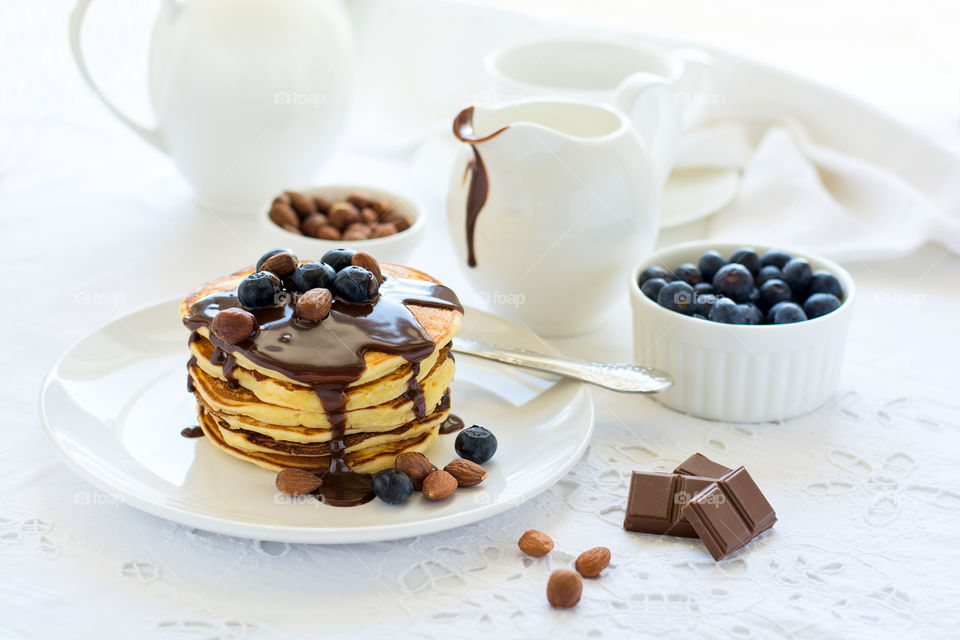 Stack of pancakes with chocolate sauce, blueberry and nuts. Healthy breakfast concept