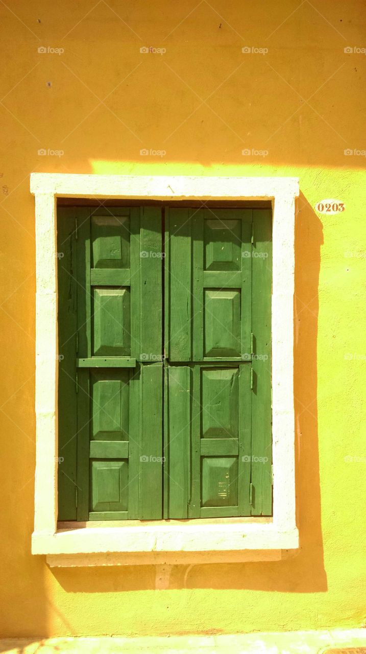 green window on the yellow wall