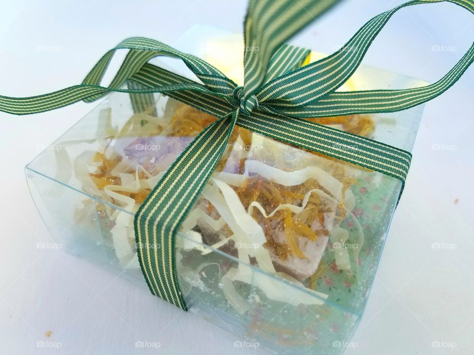 gift box of artisan soap bound by green stripe ribbon, white backdrop