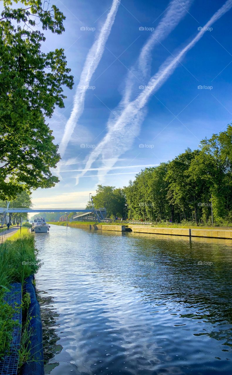 Yacht on a river between the green trees under a deep blue sky in a summer's day