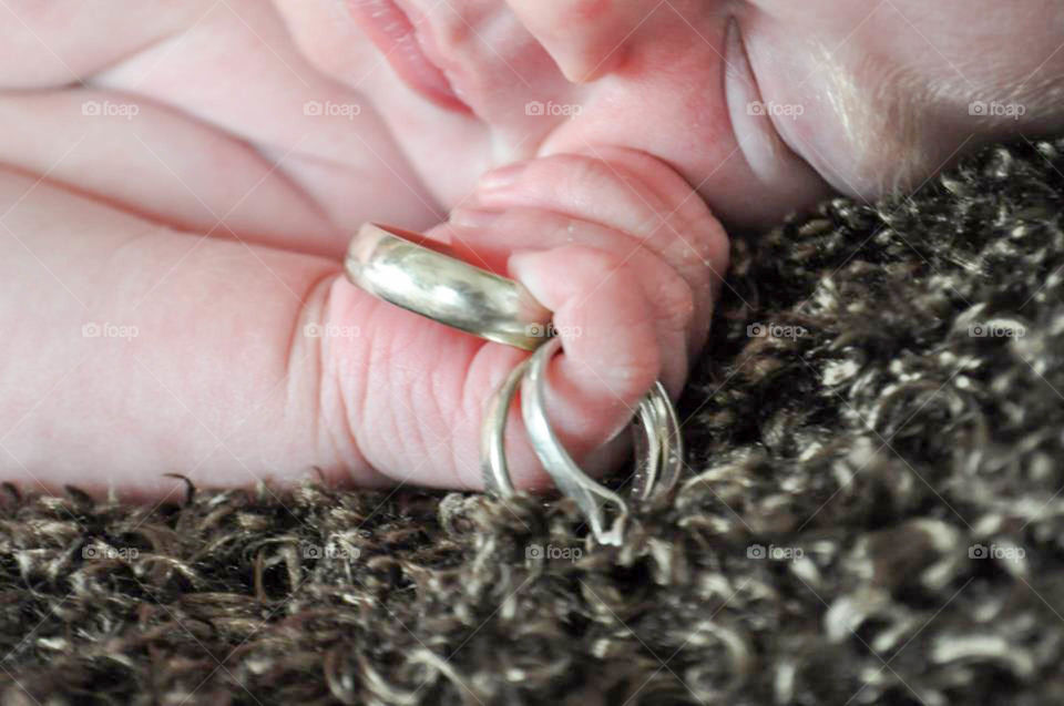 Newborn grasping wedding rings. Newborn baby - all because two people fell in love..
