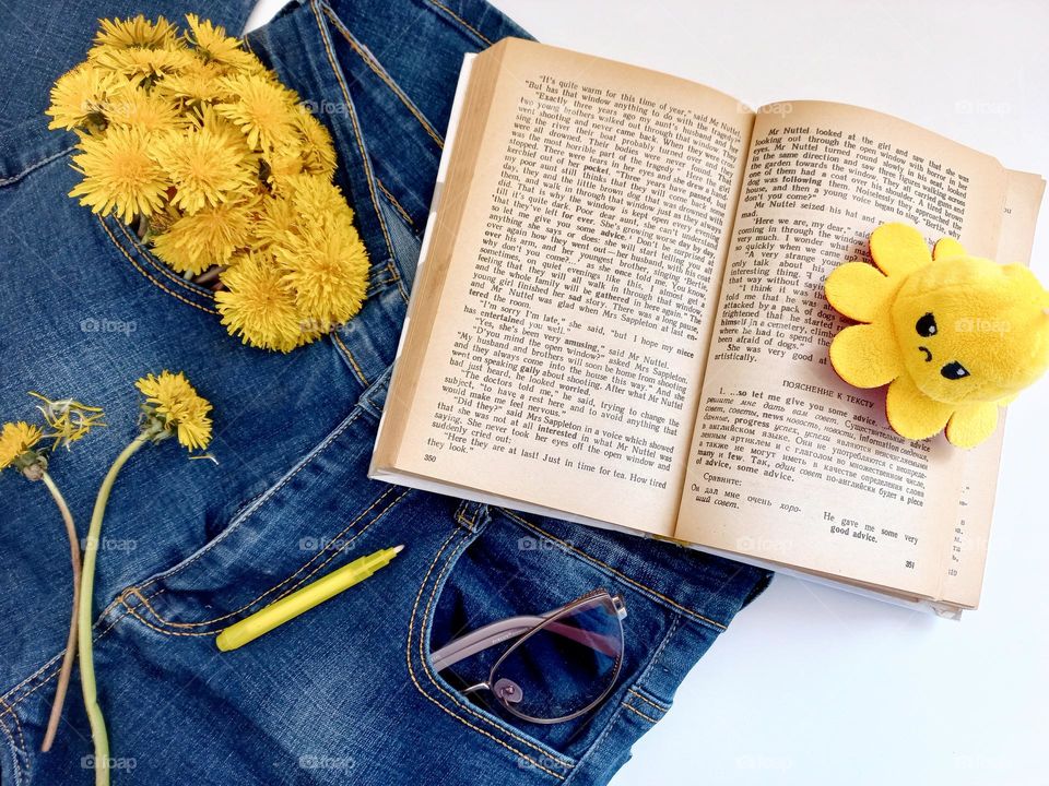 yellow dandelions, a book and a yellow keychain with a marker.
