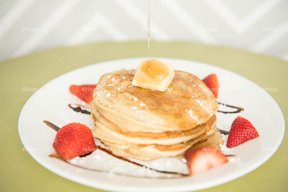 Stack of pancakes with syrup being drizzled on top