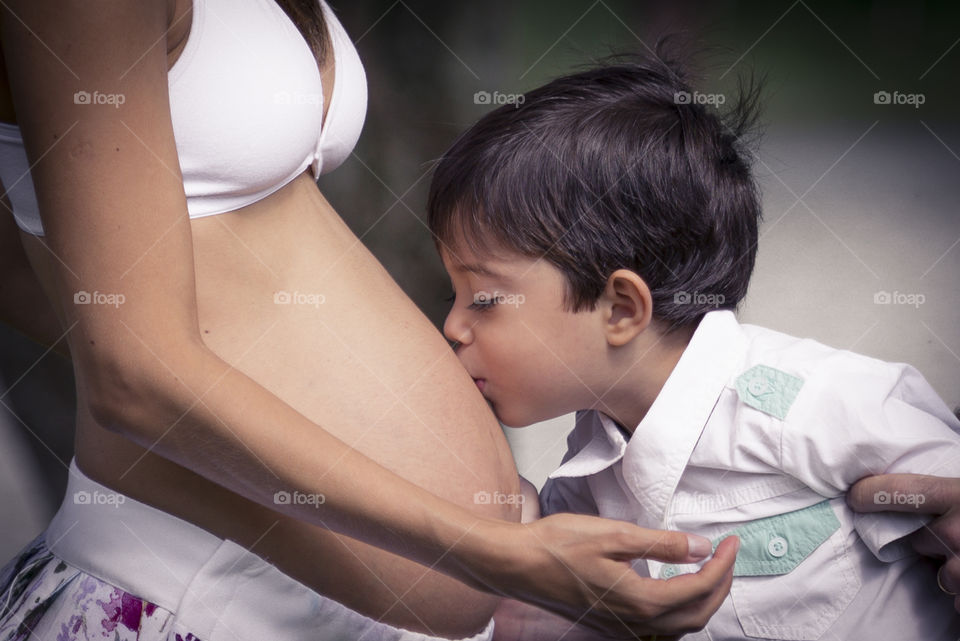 boy kissing pregnant mother's belly