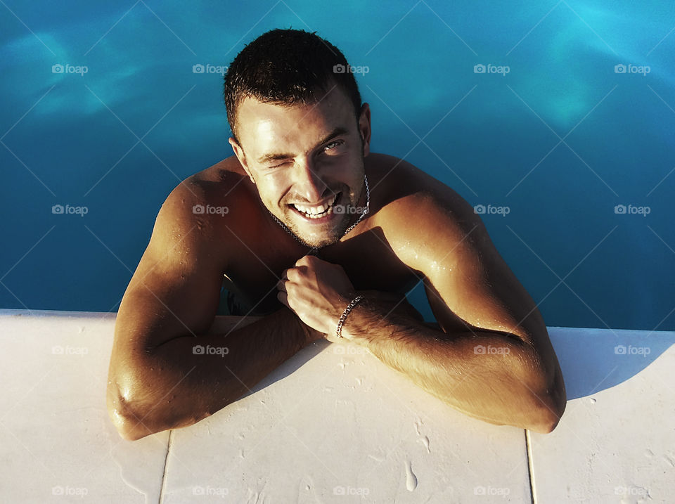 Young handsome smiling man in the swimming pool 